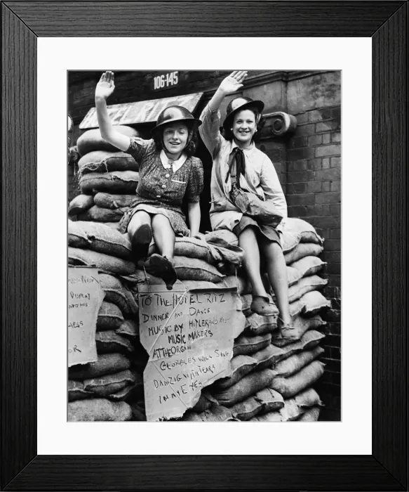 Framed Print : East End Ritz hotel, two women sitting on sand bags waving to the camera