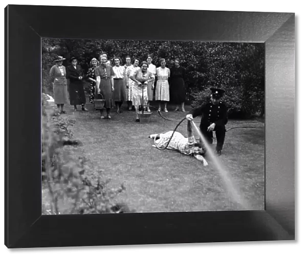 Women in Royden Grove, Lincoln Receiving Instruction in the use of a stirrup pump to put