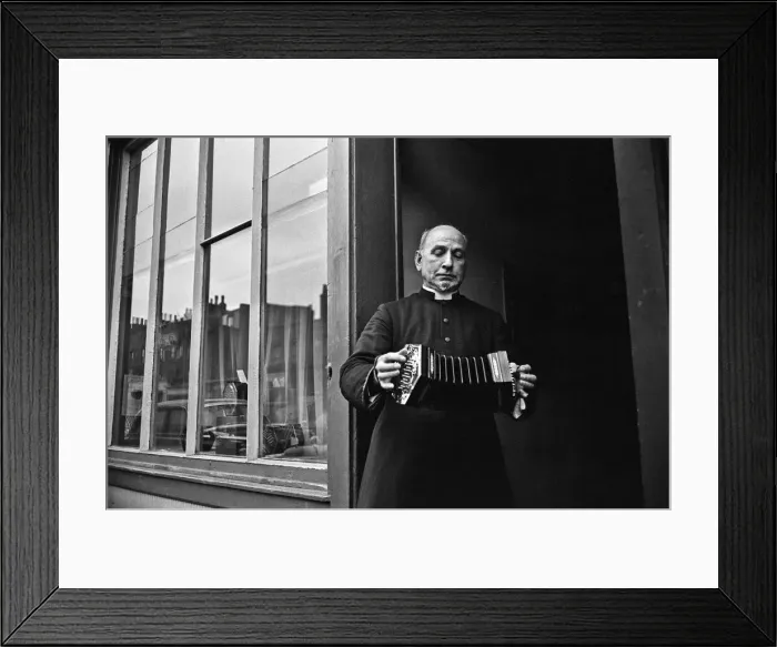 Framed Print : A priest plays a concertina outside Crabbs Concertina Shop in Liverpool Street