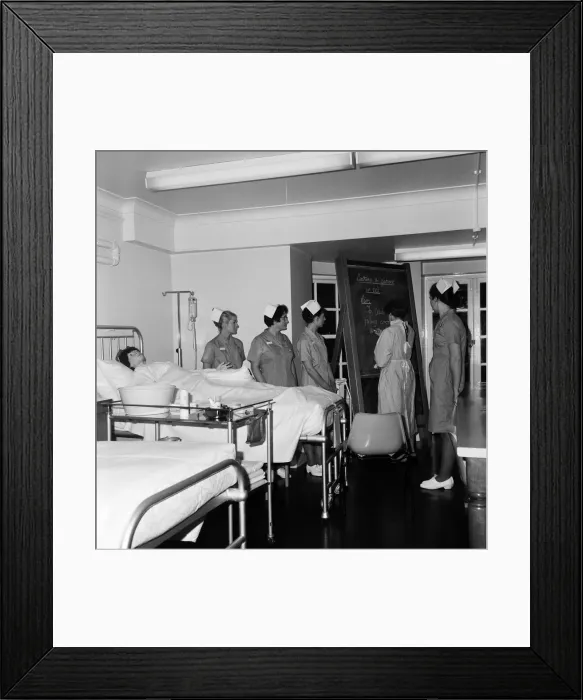 Framed Print : Nurses receiving instruction from Miss V Thomas (in surgical gown) on patient care