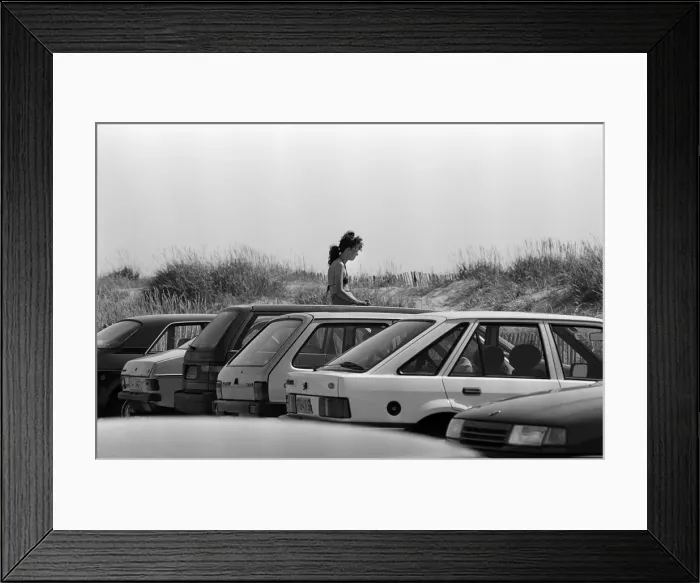 Framed Print : People enjoying a day at Crosby beach. One young lady gets a little nearer to the sun by