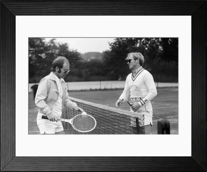 Framed Print : Elton John plays tennis against Larry King on an outer court at Wimbledon. 25th June 1974 Framed Print : Elton John plays tennis against Larry King on an outer court at Wimbledon. 25th June 1974