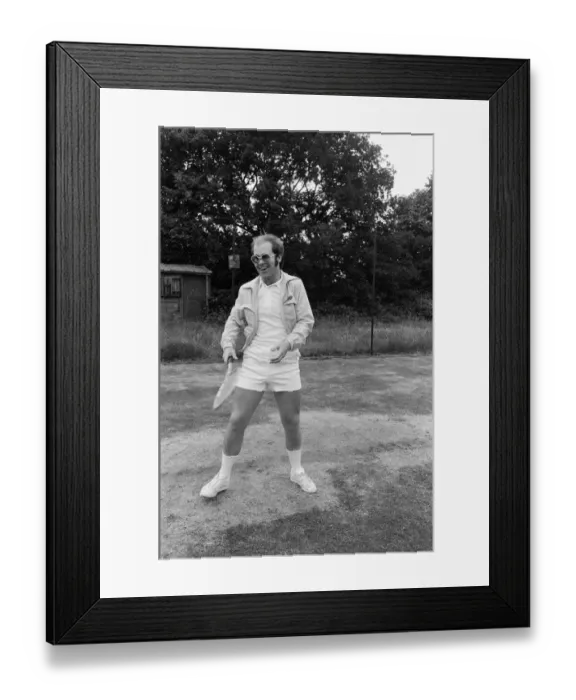 Framed Print : Elton John playing tennis on an outer court at Wimbledon. 25th June 1974 Framed Print : Elton John playing tennis on an outer court at Wimbledon. 25th June 1974