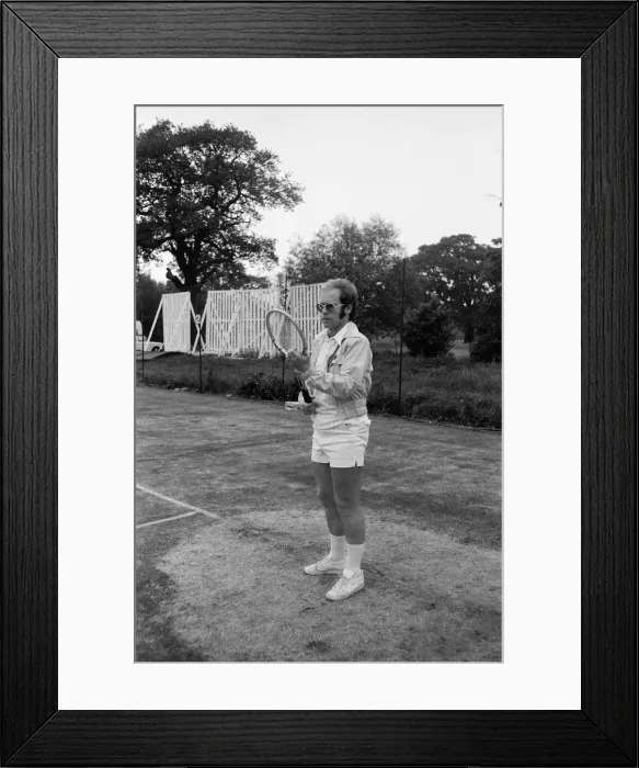 Framed Print : Elton John playing tennis on an outer court at Wimbledon. 25th June 1974 Framed Print : Elton John playing tennis on an outer court at Wimbledon. 25th June 1974