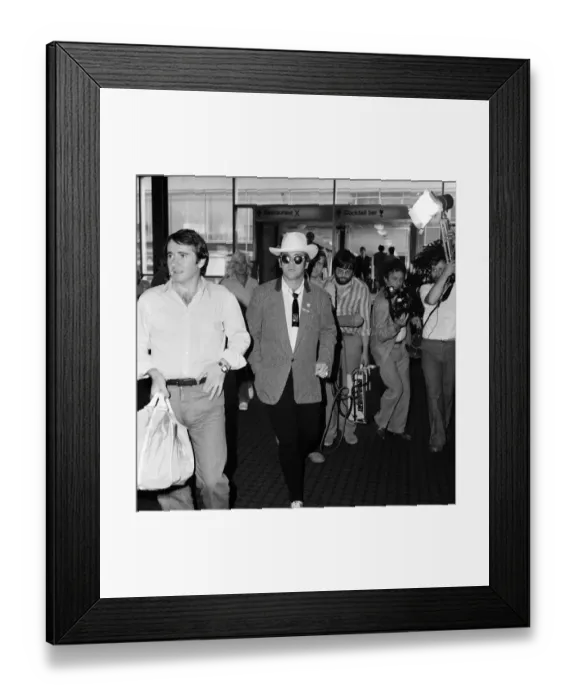 Framed Print : Dressed in a stetson hat, Elton John leaves Heathrow Airport for America