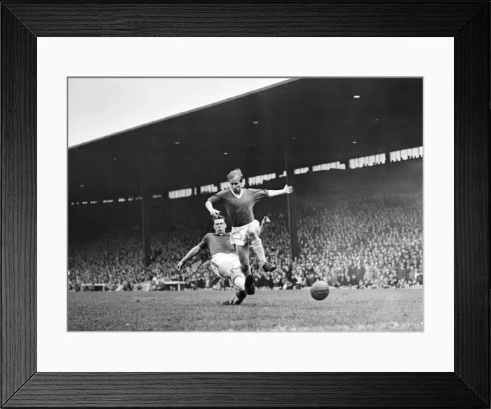 Framed Print : Bobby Charlton leaps to elude a defender during the match between Manchester United