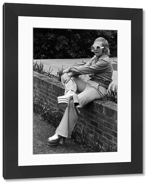 Elton John, singer, pictured at home in Virginia Water. He is wearing platform boots