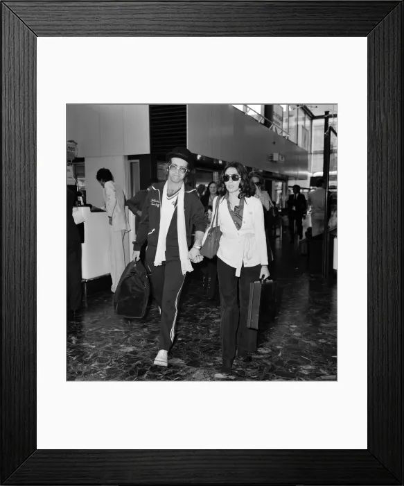 Framed Print : Elton John leaving Heathrow airport hand in hand with Connie Papras Framed Print : Elton John leaving Heathrow airport hand in hand with Connie Papras