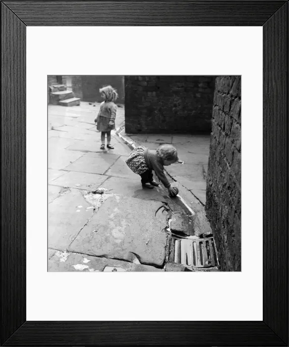 Framed Print : Slum living conditions in the north west of England. Two children playing with a ball Framed Print : Slum living conditions in the north west of England. Two children playing with a ball