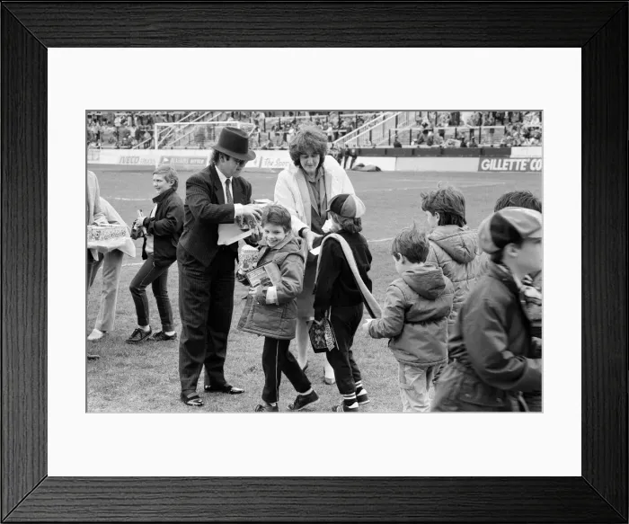 Framed Print : Pop star and Watford FC Chairman, Elton John, handing out Easter eggs to fans