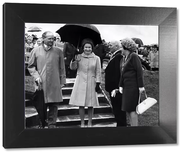 Queen Elizabeth II walks from the tree planting at Werneth Low carrying an umbrella to