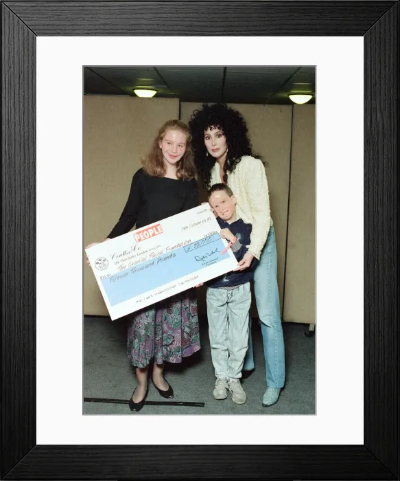 Framed Print : Cher, American singer, presents cheque for 15, 000 pounds to representatives of