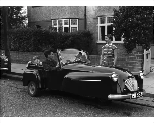 A father takes his son for a ride in his new convertible Bond mini car. Circa 1950