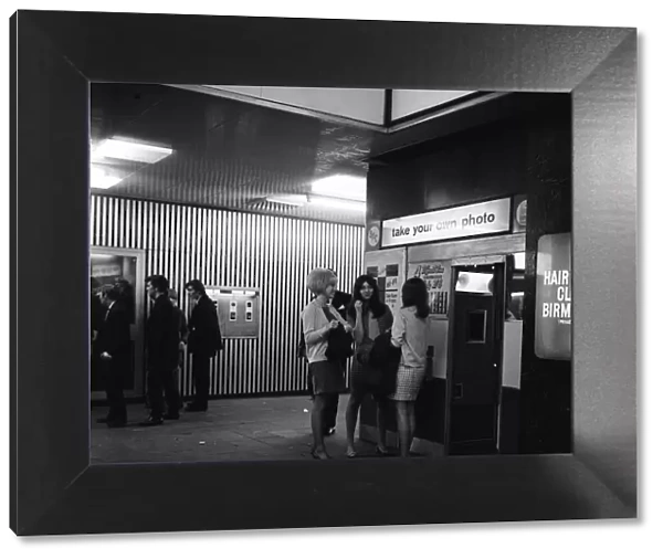 Women standing outside a photo booth in Birmingham, West Midlands. 4th October 1967