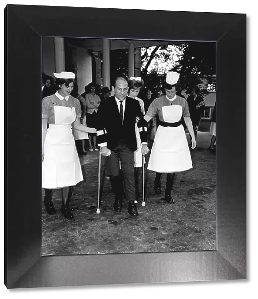 Stirling Moss motor racing driver leaving hospital 1962 on crutches with help of