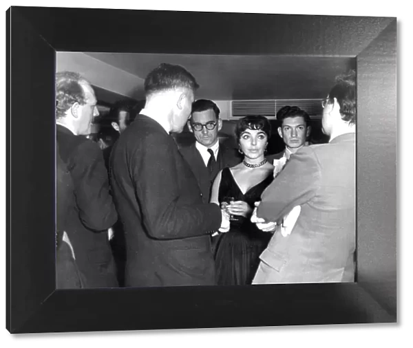 Joan Collins among crowd of reporters at press event at the Savoy Hotel - October 1955