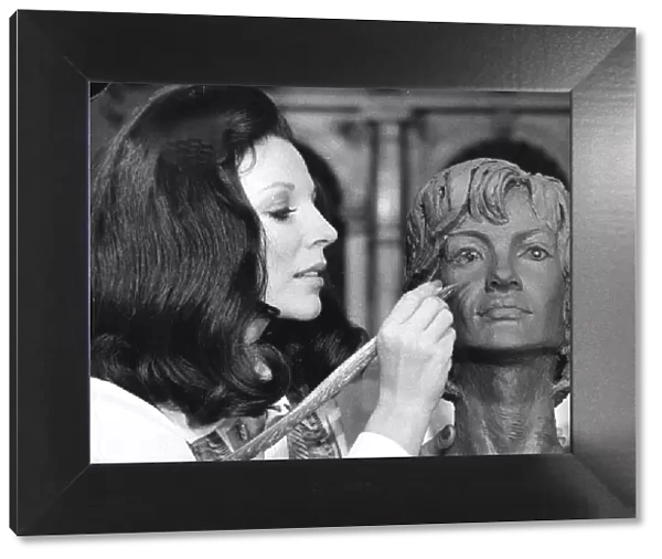 Joan Collins working on a clay bust during filming at Elstree Studios