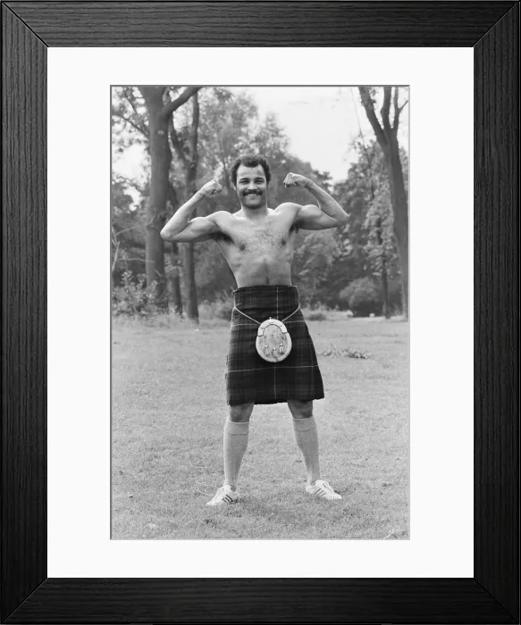 Framed Print : John Conteh gets the Scottish flavour on Parliament Hill Fields today watched by curious