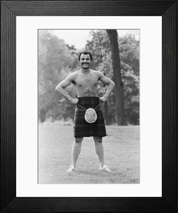 Framed Print : John Conteh gets the Scottish flavour on Parliament Hill Fields today watched by curious
