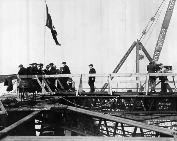 Construction of the new Tyne Bridge. Hoisting the Union Jack on the top after the joining