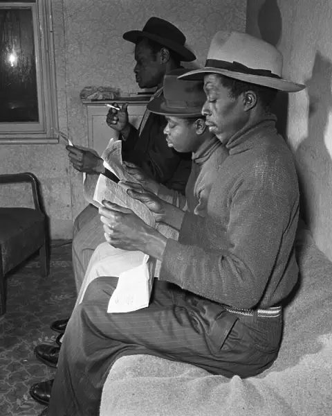 Young West Indian men in Brixton looking through the small ads in the local newspapers
