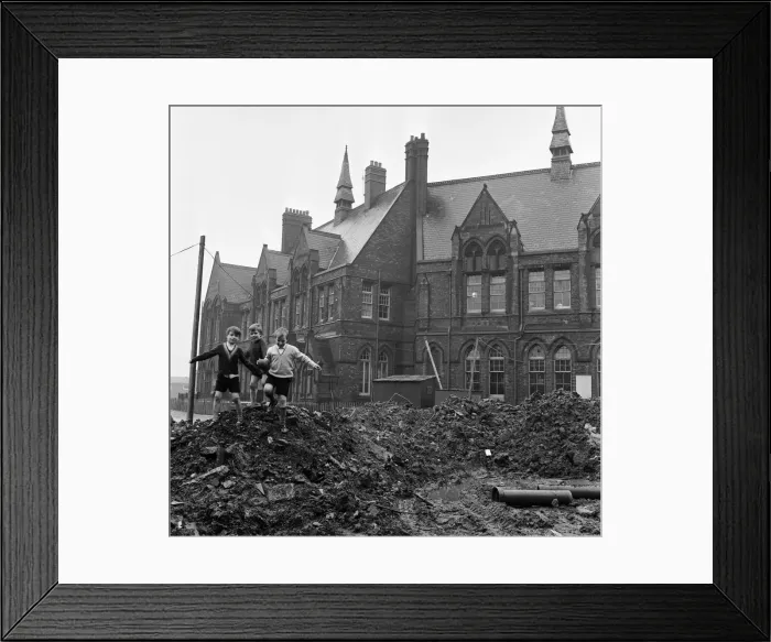 Framed Print : Pupils of Ross Place School, Ardwick, Manchester, jump across a sea of mud to enter Framed Print : Pupils of Ross Place School, Ardwick, Manchester, jump across a sea of mud to enter