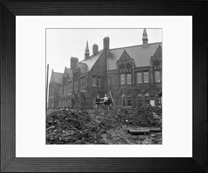 Framed Print : Pupils of Ross Place School, Ardwick, Manchester, jump across a sea of mud to enter Framed Print : Pupils of Ross Place School, Ardwick, Manchester, jump across a sea of mud to enter