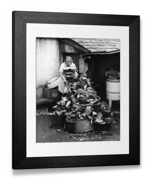 Framed Print : Picture shows a lady salvaging a variety of goods, such as pots and pans, plates, china
