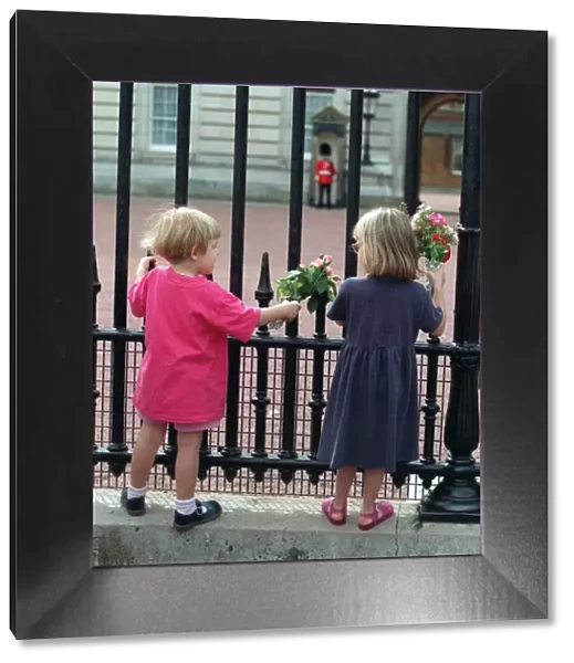 YOUNG CHILDREN OUTSIDE THE GATES OF BUCKINGHAM PALACE HOLDING FLOWERS IN TRIBUTE FOR THE