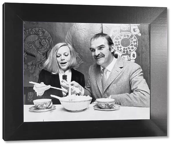 Honor Blackman and Stanley Baker eating food with chopsticks in Chinese restaurant