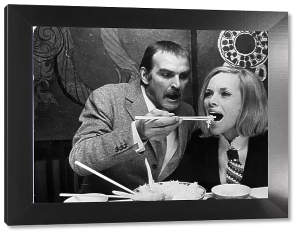 Honor Blackman and Stanley Baker eating food with chopsticks in Chinese restaurant