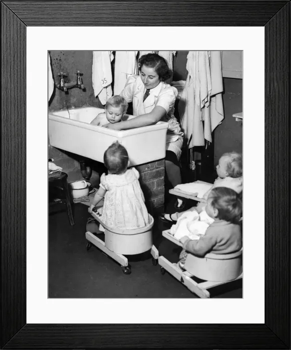 Framed Print : Salisbury day nursery. A woman bathing a child, with other seated children watching Framed Print : Salisbury day nursery. A woman bathing a child, with other seated children watching