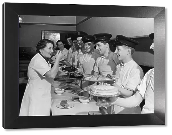 Women cookery experts teach men at a naval school. Naval ratings are taught by ex-school