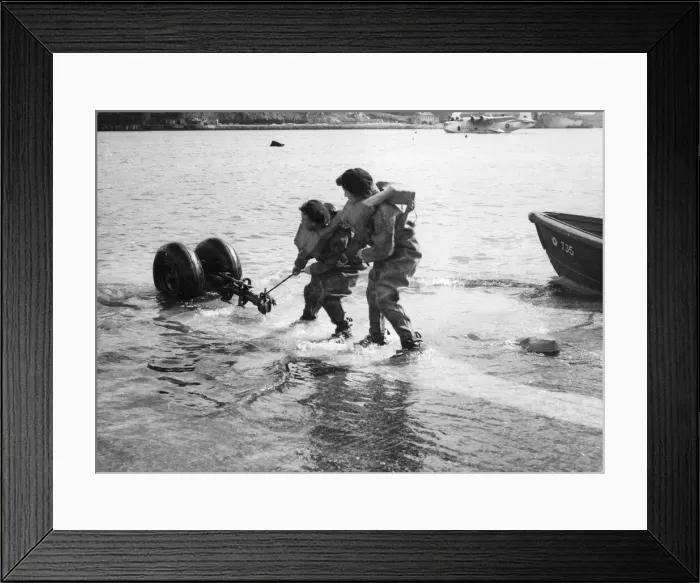 Framed Print : Two rubber clad flight mechanics hold part of the breaching a gear Framed Print : Two rubber clad flight mechanics hold part of the breaching a gear