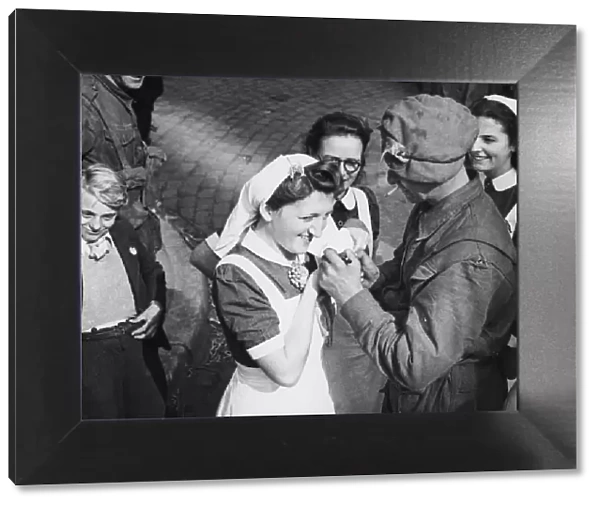 A British soldier autographs the cap of a Dutch nurse at Eindhoven as a souvenir of