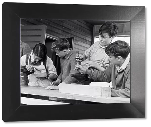 Evacuee children repairing shoes. 7th May 1940