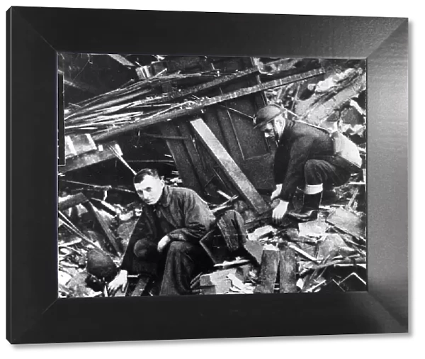 Two members of the emergency services sift through the rubble after another air raid