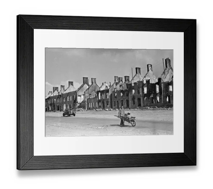 Framed Print : A civilian pushes a wheelbarrow of salvaged belongings amidst the ruined buildings