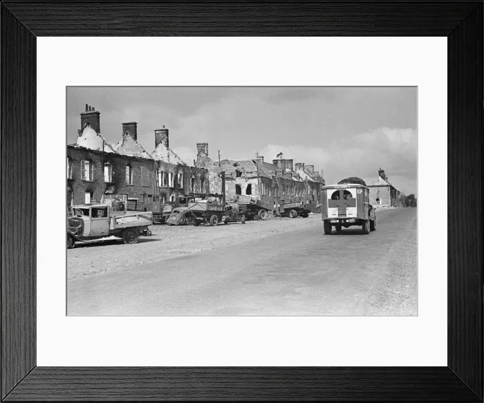 Framed Print : A US army ambulance drives pass the ruined buildings and wrecked German transport in