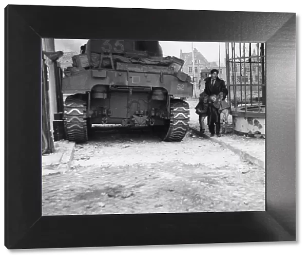 A British Sherman tank pauses for a moment as a Dutch civilian lifts his two children