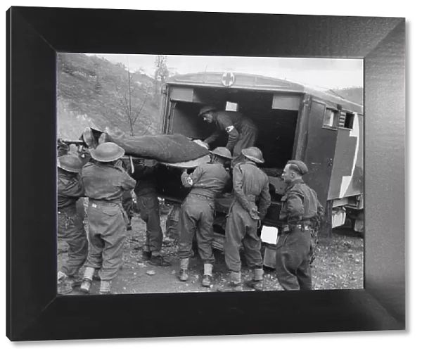 A 8th Army casualty being loaded into a motor ambulance