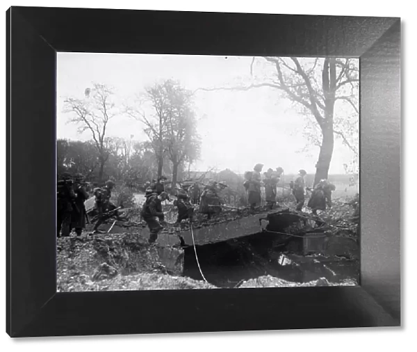 An Allied patrol moves across a damaged bridge over the River Meuse near Broekhuizen