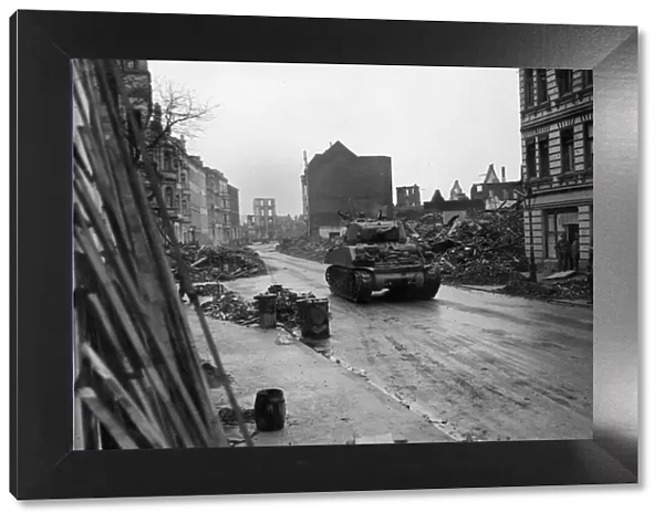 An American tank rumbles through a wreckage lined street on the outskirts of