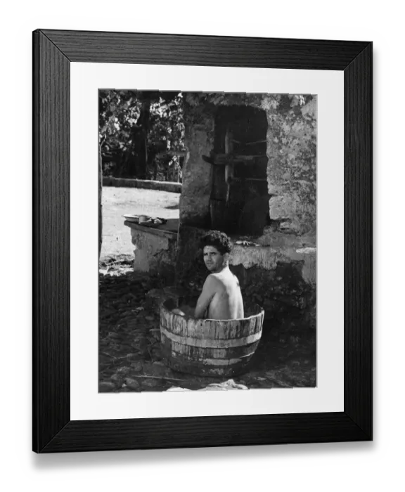 Framed Print : An RAF Airman takes a bath in a wooden tub on the cobbles beside the pump Framed Print : An RAF Airman takes a bath in a wooden tub on the cobbles beside the pump
