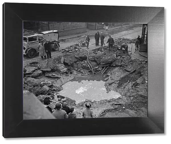 Workmen pump out a flooded bomb crater in the centre of Birmingham following an air raid