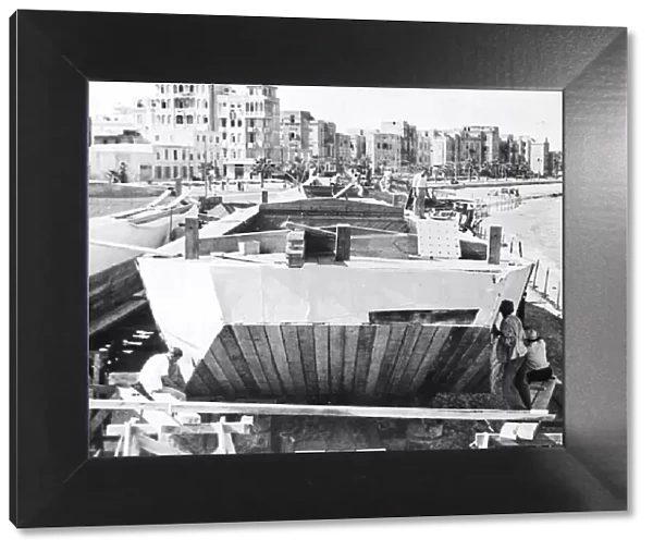Alexandria, Egypt. Canvas being nailed onto the sides of a flat bottomed barge called a