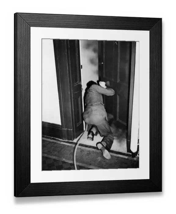 Framed Print : How to extinguish a fire bomb. A man crouches in the doorway of a smoke filled room Framed Print : How to extinguish a fire bomb. A man crouches in the doorway of a smoke filled room