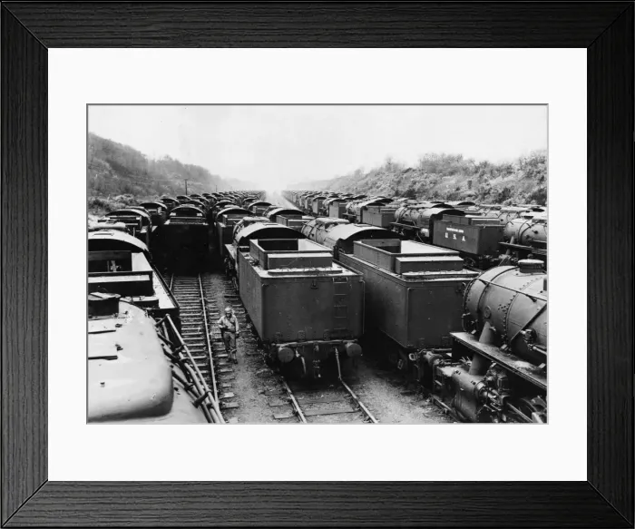 Framed Print : An American soldier stands on guard, surrounded American built locomotives at a rail