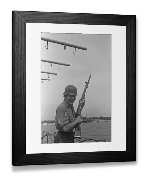 Framed Print : Sailor on a landing craft poses with a captured German helmet