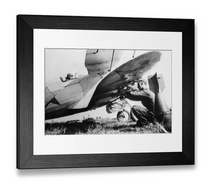 Framed Print : A Soviet pilot sits at his controls while bombs are attached to his aircraft